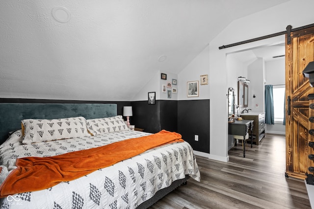 bedroom featuring a barn door, baseboards, vaulted ceiling, and wood finished floors