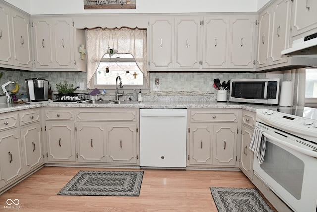 kitchen with light countertops, a sink, light wood-type flooring, white appliances, and under cabinet range hood