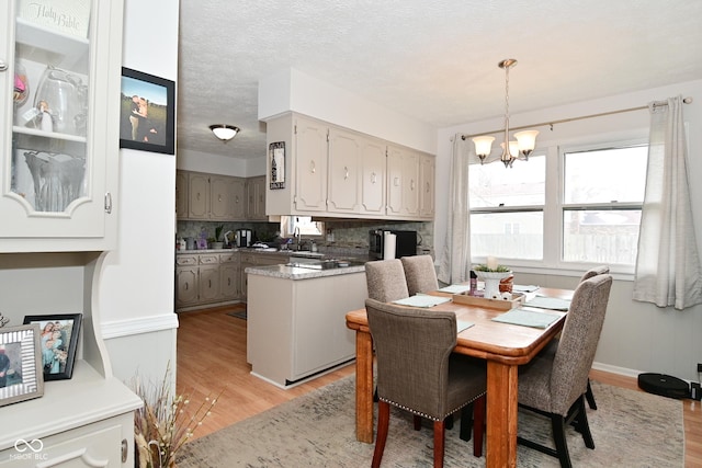 dining area featuring a textured ceiling, light wood-type flooring, baseboards, and a notable chandelier