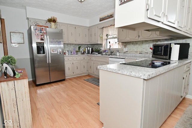 kitchen with stainless steel appliances, a peninsula, light countertops, and light wood-style flooring