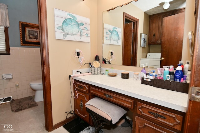 bathroom featuring visible vents, toilet, washer / clothes dryer, vanity, and tile walls