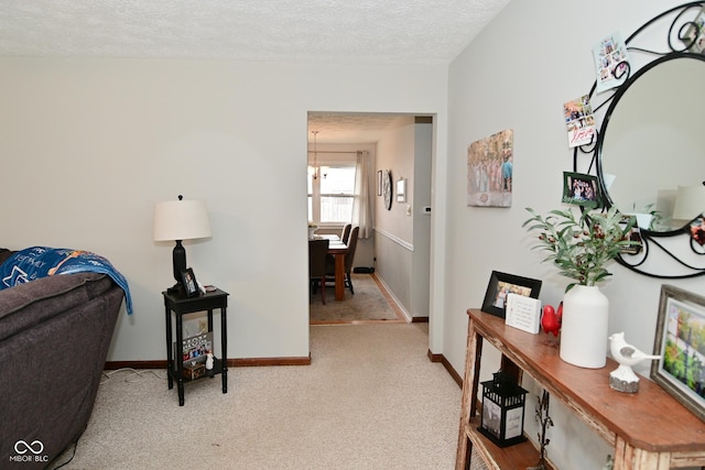 interior space featuring a textured ceiling, baseboards, and light colored carpet