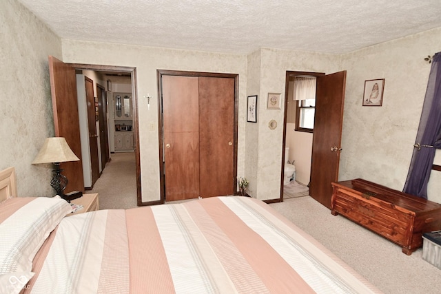 carpeted bedroom featuring a closet, a textured ceiling, and ensuite bathroom