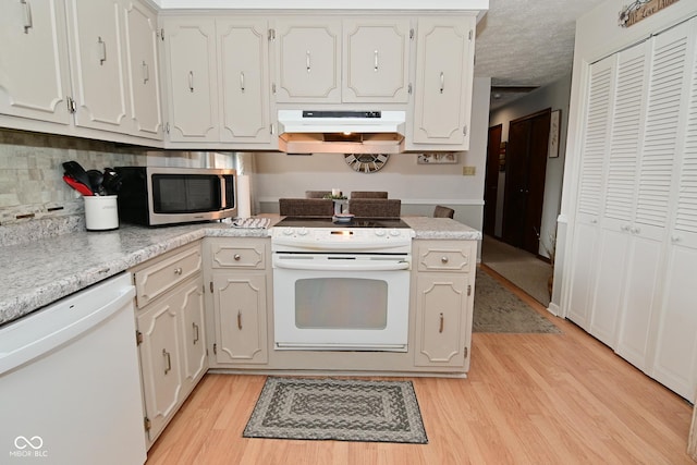 kitchen with white appliances, under cabinet range hood, white cabinetry, and light countertops