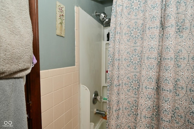 bathroom with a wainscoted wall, tile walls, and shower / bath combo with shower curtain