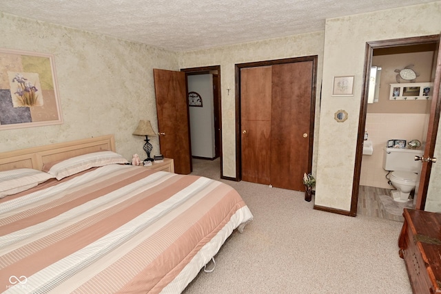 bedroom featuring a closet, light carpet, connected bathroom, and a textured ceiling