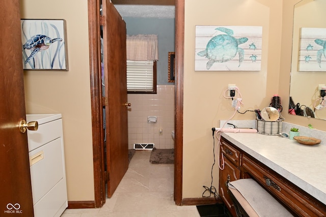 bathroom featuring tile walls, washer / clothes dryer, visible vents, and vanity