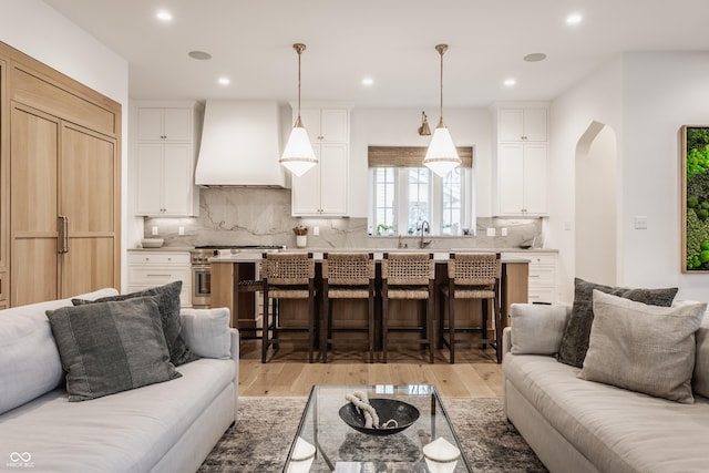 living room featuring light wood finished floors, arched walkways, and recessed lighting