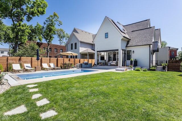 rear view of house with a patio, a lawn, fence, and a fenced in pool