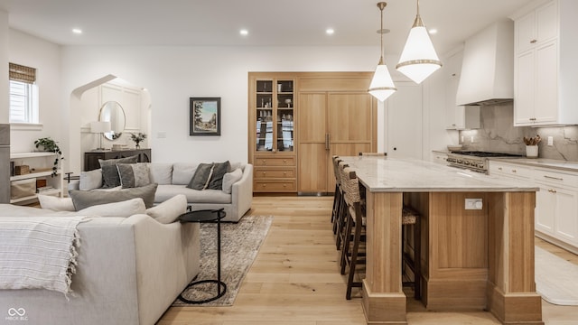 living room with light wood-type flooring, arched walkways, and recessed lighting