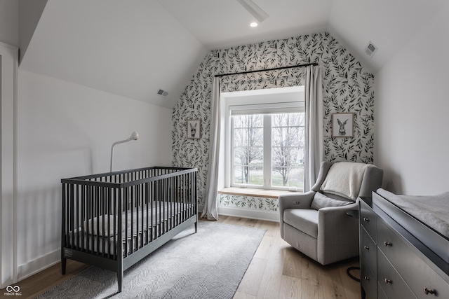 bedroom featuring wallpapered walls, vaulted ceiling, visible vents, and light wood finished floors