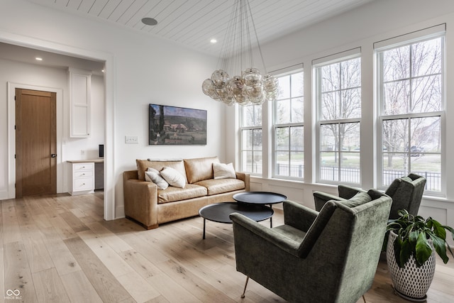 living room with light wood-type flooring, a healthy amount of sunlight, recessed lighting, and an inviting chandelier