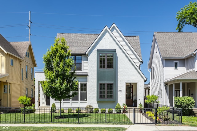 view of front of house featuring a fenced front yard, roof with shingles, brick siding, and a front lawn