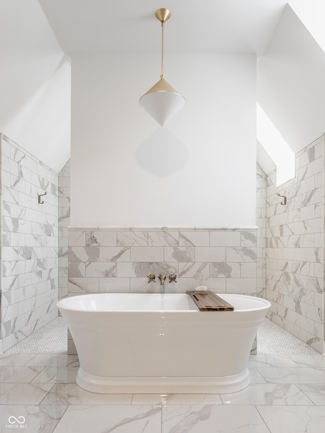 full bathroom with marble finish floor, tile walls, a tile shower, and a freestanding bath