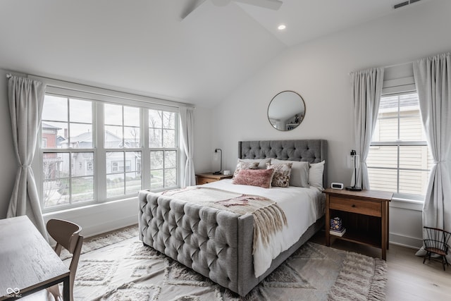 bedroom featuring multiple windows, vaulted ceiling, baseboards, and wood finished floors