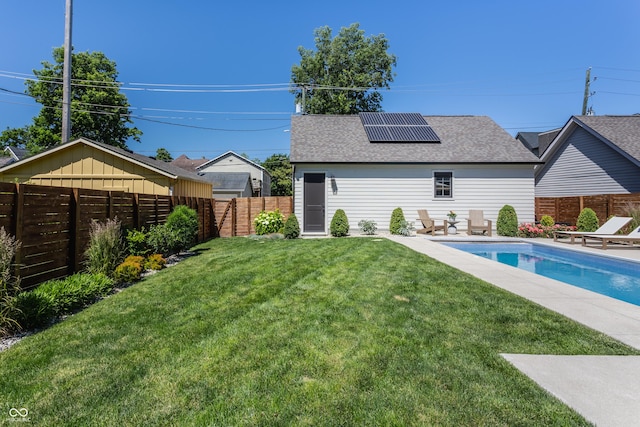 back of property with a fenced backyard, solar panels, a lawn, a fenced in pool, and a patio area