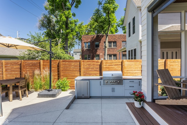 view of patio featuring area for grilling, a grill, and fence