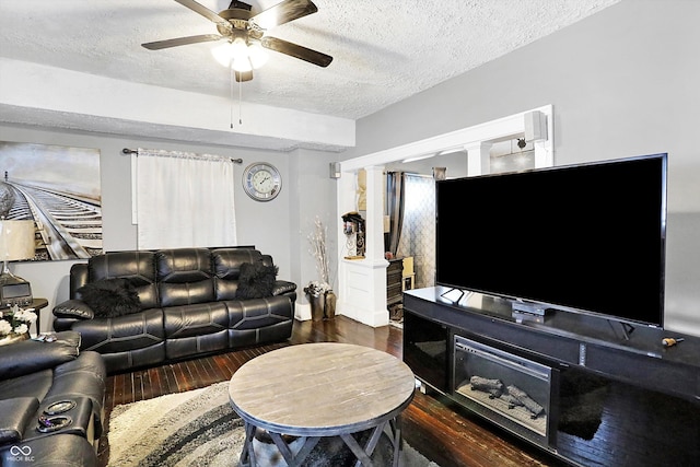 living area with ornate columns, ceiling fan, a textured ceiling, and wood finished floors