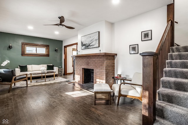 living area with a brick fireplace, ceiling fan, stairway, recessed lighting, and wood finished floors