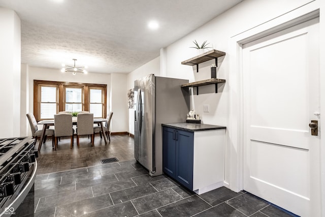 kitchen featuring blue cabinets, open shelves, range with gas stovetop, dark countertops, and a textured ceiling