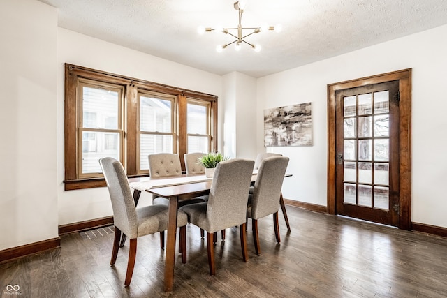 dining space featuring an inviting chandelier, baseboards, dark wood-type flooring, and a textured ceiling