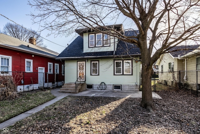 back of property with a patio, a shingled roof, and fence