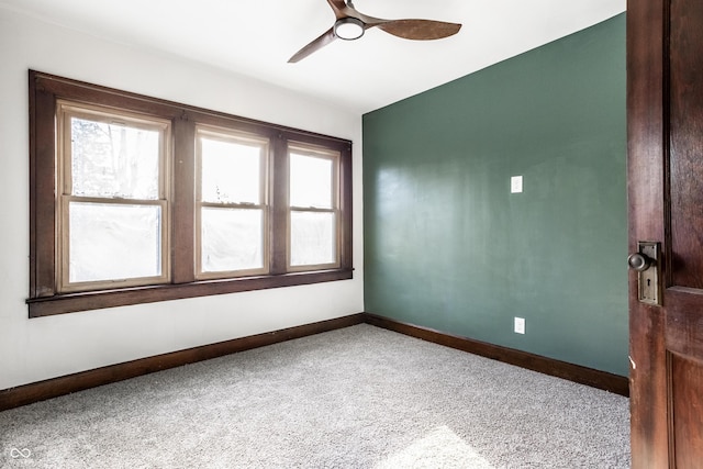 empty room with carpet flooring, a ceiling fan, and baseboards