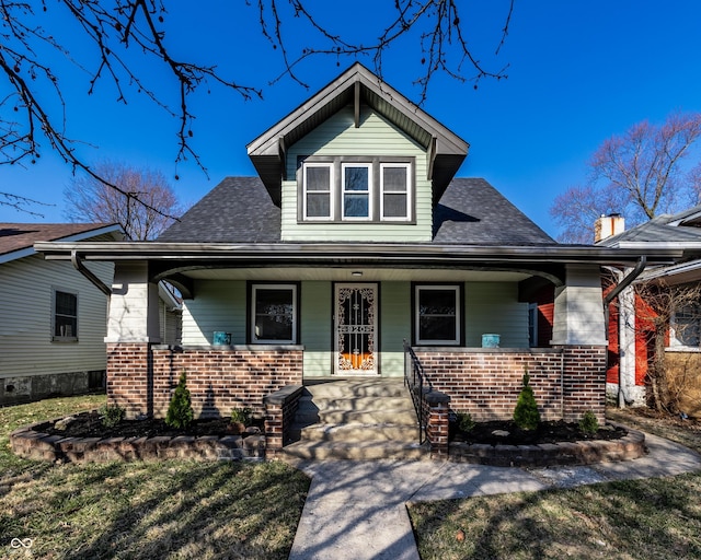 bungalow featuring brick siding, a porch, and a shingled roof