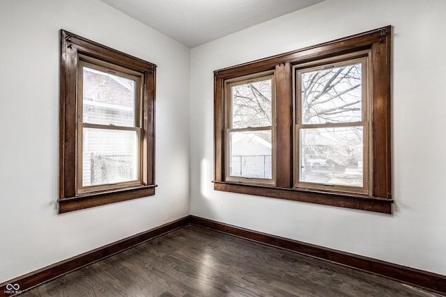 spare room featuring dark wood finished floors and baseboards