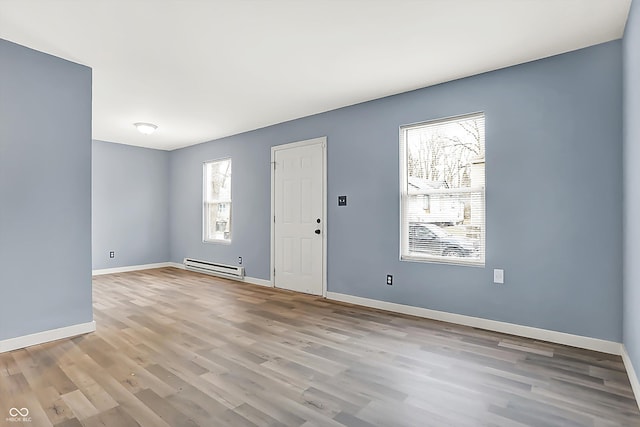 interior space featuring light wood-type flooring, a baseboard radiator, and baseboards