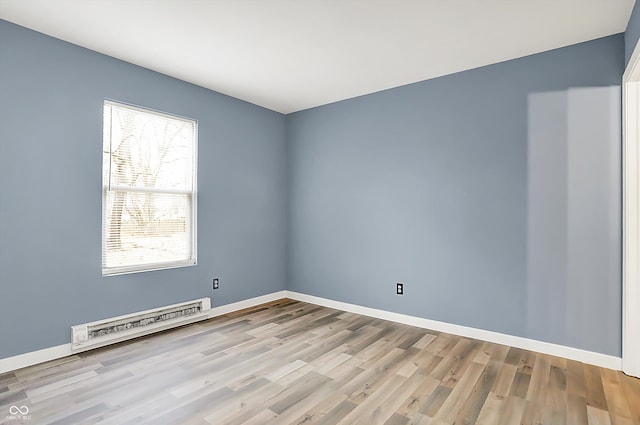 unfurnished room featuring baseboards, a baseboard heating unit, and wood finished floors