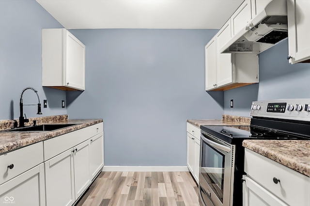 kitchen featuring under cabinet range hood, a sink, light wood-style floors, white cabinets, and stainless steel electric range