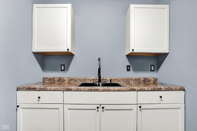 kitchen featuring dark countertops, white cabinets, and a sink