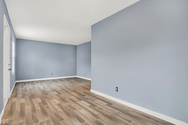 spare room with baseboards and wood finished floors