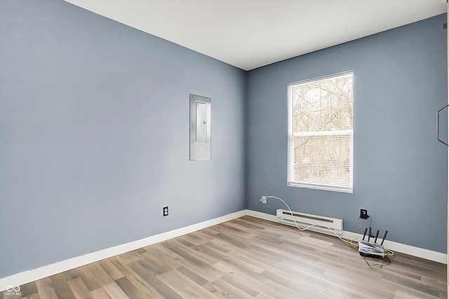 unfurnished room with light wood-style floors, electric panel, a baseboard heating unit, and baseboards