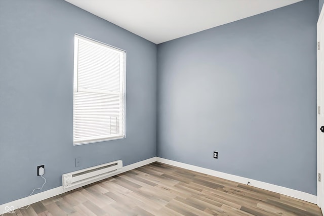 empty room featuring a baseboard radiator, baseboards, and wood finished floors