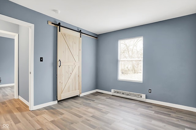 unfurnished bedroom with visible vents, light wood-style flooring, baseboards, and a barn door