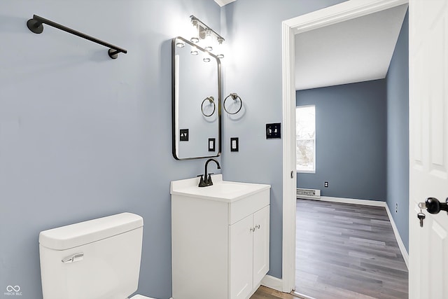 bathroom with toilet, baseboards, wood finished floors, and vanity