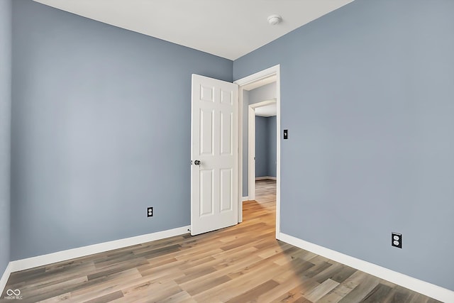 spare room featuring light wood-type flooring and baseboards