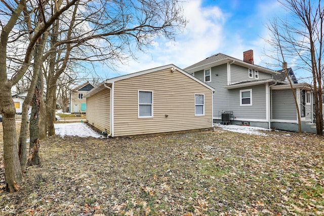 rear view of property featuring central AC and a chimney