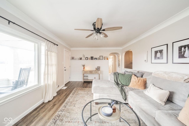 living area featuring baseboards, arched walkways, a ceiling fan, ornamental molding, and wood finished floors