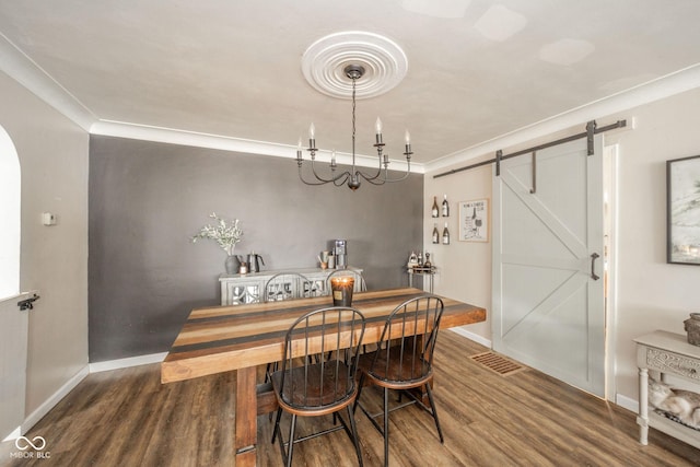 dining space with wood finished floors, crown molding, baseboards, and a barn door