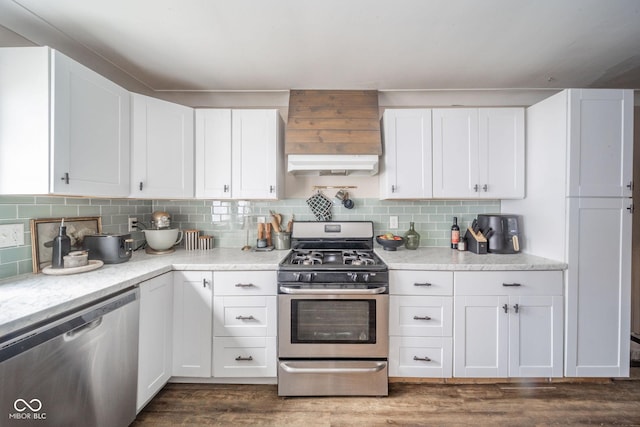 kitchen with appliances with stainless steel finishes, white cabinetry, under cabinet range hood, and tasteful backsplash