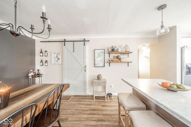 dining area featuring a barn door, wood finished floors, and baseboards