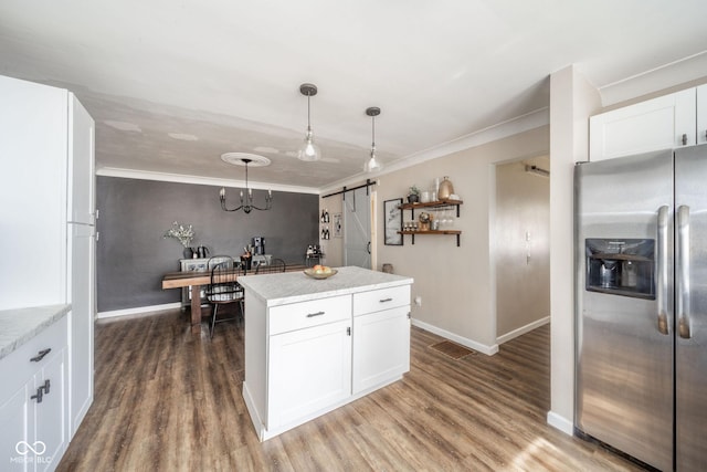 kitchen with a barn door, wood finished floors, white cabinets, and stainless steel fridge with ice dispenser