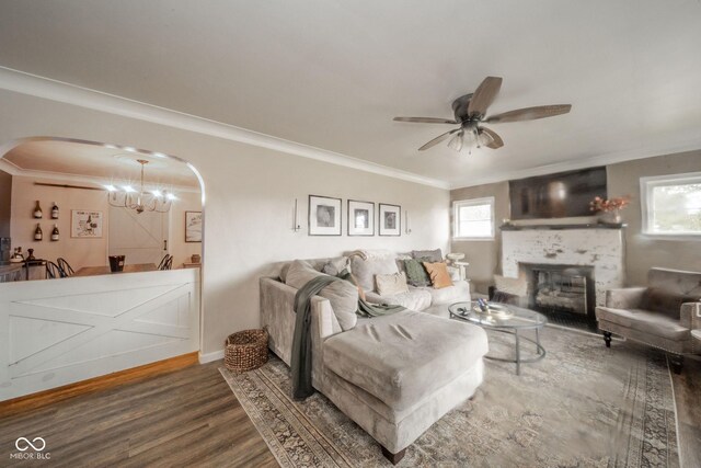 living area with a wealth of natural light, arched walkways, crown molding, and wood finished floors