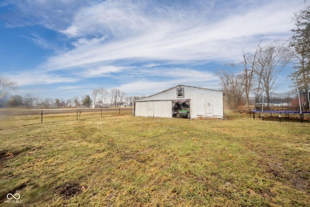 view of yard with a trampoline, fence, an outbuilding, and an outdoor structure