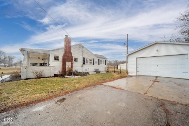 view of home's exterior with a garage, a chimney, an outdoor structure, and a yard