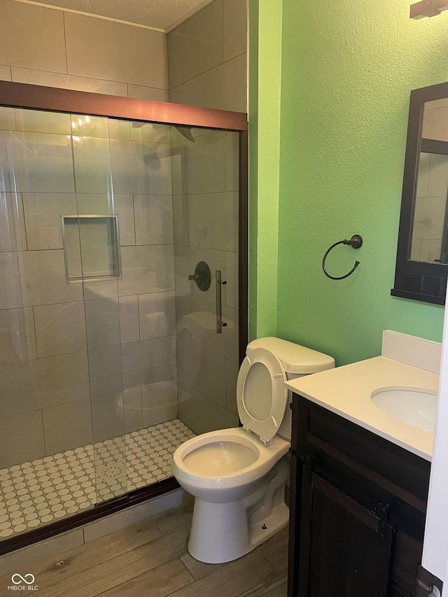 full bathroom featuring toilet, a shower stall, vanity, and wood finished floors