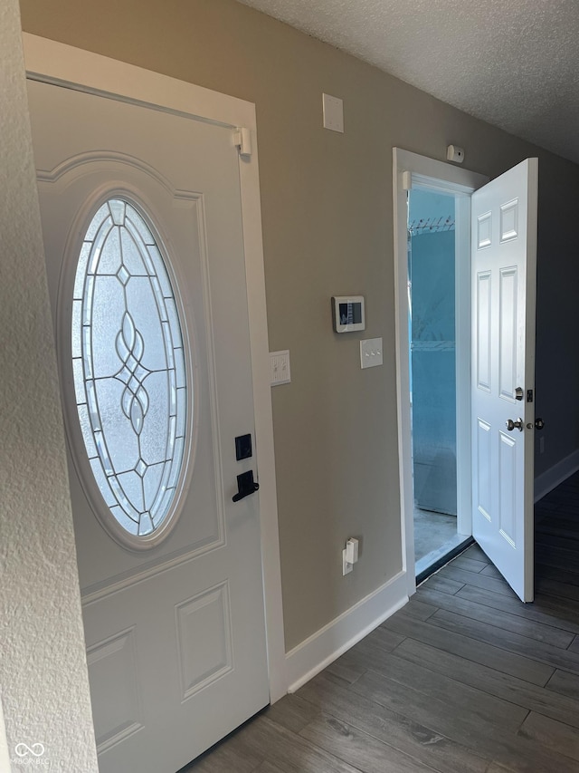 entryway with baseboards, dark wood finished floors, and a textured ceiling